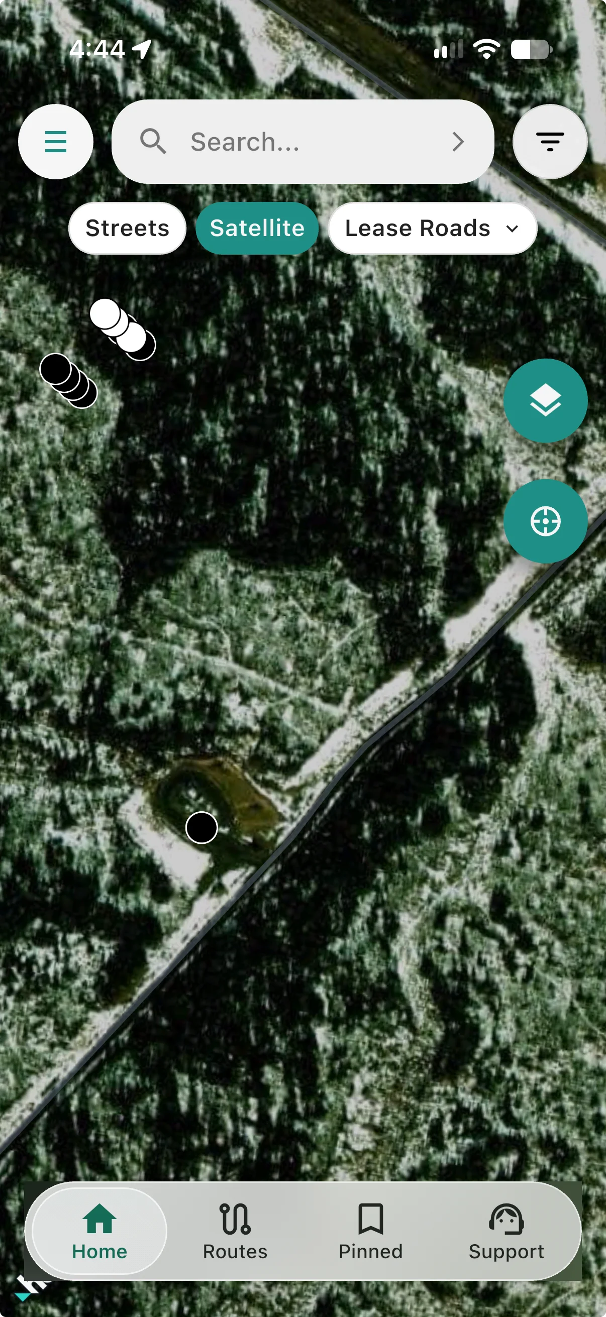Satellite imagery in winter with well markers over forest and an older pad beside the road